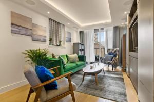a living room with a green couch and a table at Canal Side Luxury 1 Bed Chelsea in London