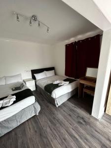 a bedroom with two beds and a table with a chair at The Ruislip Apartment in Ruislip