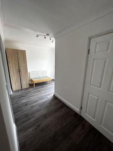 an empty room with a door and a bench at The Ruislip Apartment in Ruislip