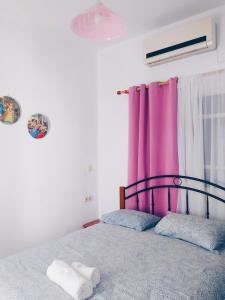 a bedroom with a bed with a purple curtain at Villa Irene in Kalymnos