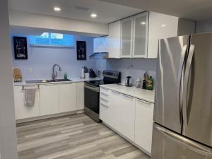 una cucina con armadi bianchi e frigorifero in acciaio inossidabile di Gilford Beach Apartment a Innisfil