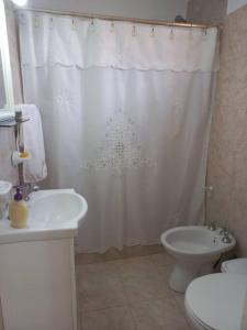 a bathroom with a white shower curtain and a toilet at Departamento impecable. con cochera in Luján