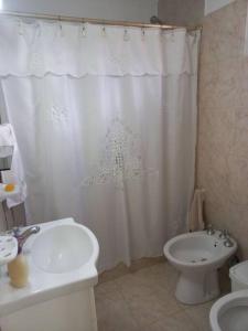 a bathroom with a white shower curtain and a toilet at Departamento impecable. con cochera in Luján