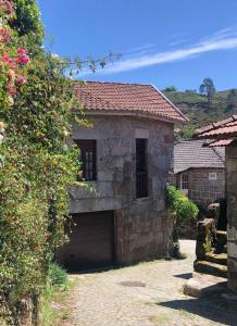 a stone house with a garage in a yard at Casa Maria in Terras de Bouro