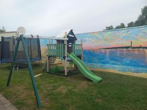 a playground with a slide in front of a mural at Residencial La Teja in Zahora
