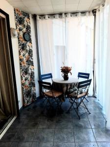 a table and chairs in a room with windows at Charmante maison de ville avec jardin in Perpignan