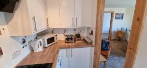 una cucina con armadietti bianchi e forno a microonde di Colin Young Place a Nairn
