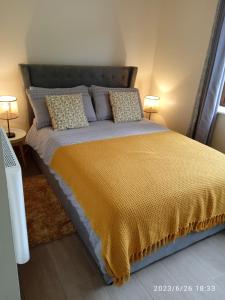 a bedroom with a bed with a yellow bedspread and two lamps at Nire Valley Cottage 