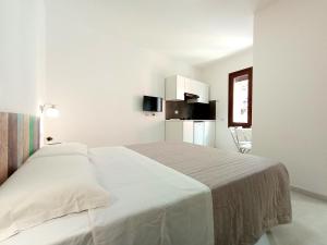 a white bedroom with a bed and a refrigerator at Monolocali Cavour - Affitti Brevi Italia in Ulassai