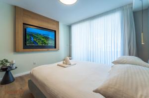 a bedroom with a large bed and a tv on the wall at Sea side "Tulip" apartment - by Rently in Eilat