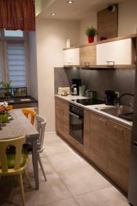 Lukas Guest Rooms في كراكوف: مطبخ مع دواليب خشبية وطاولة مع غرفة طعام