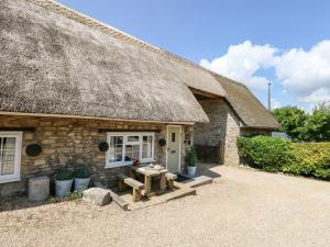 a stone cottage with a thatched roof with a table outside at Magnolia Cottage Osmington in Osmington