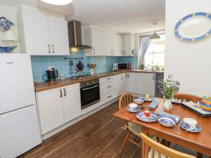 a kitchen with white cabinets and a wooden table at The Coach House in Ridingmill