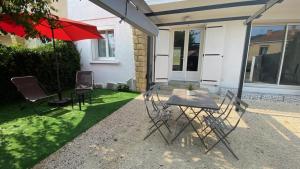 a patio with a table and chairs and an umbrella at La perle de provence, appartement neuf en rez de Jardin clos, au calme, clim, salle d'eau dans chaque chambre, à 900m du centre de Nyons in Nyons