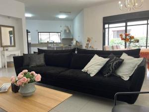 a black couch in a living room with a table at וילה מפנקת ומאובזרת במיקום מעולה in Giv'at Avni