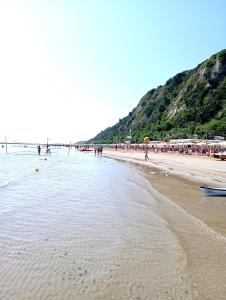 a beach with a group of people standing in the water at B&B Profumo Di Gelsomino in Mombaroccio