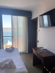 ein Hotelzimmer mit einem Bett, einem Schreibtisch und einem Fenster in der Unterkunft Panorama Hotel in Muggia
