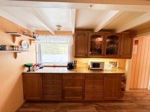 a kitchen with wooden cabinets and a microwave at Svingen Guesthouse - Panoramic Fjord Views in Flåm in Flåm