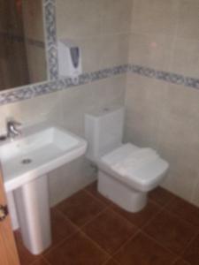 y baño con aseo blanco y lavamanos. en Cueva Restaurante Itariegos en Villagallegos