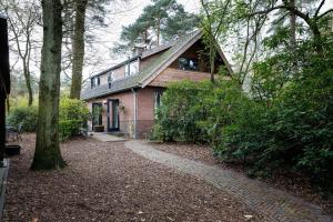 Ein Haus im Wald mit einem Weg, der dahin führt. in der Unterkunft B&B Wicherumloo in Wekerom