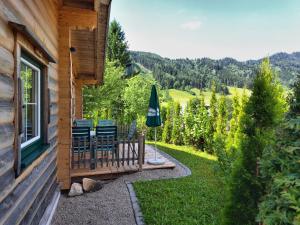 eine Veranda eines Blockhauses mit Stühlen und einem Sonnenschirm in der Unterkunft Almdorf im Winkl - Blockhüttendorf in Gröbming in Gröbming