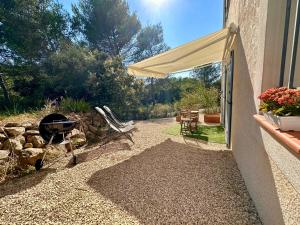 - une terrasse avec un barbecue et un barbecue à côté d'un bâtiment dans l'établissement Paisible studio tout neuf en lisière de forêt, à Peyrolles-en-Provence