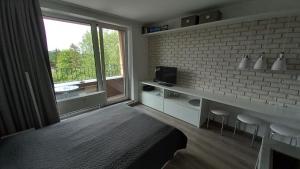 a room with a bed and a tv and a brick wall at Mountain View Studio Apartment in Poprad