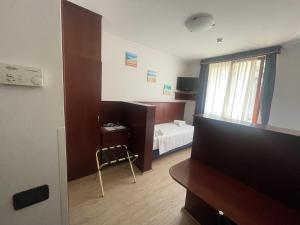 Zimmer mit einem Schlafzimmer mit einem Bett und einem TV in der Unterkunft Panorama Hotel in Muggia