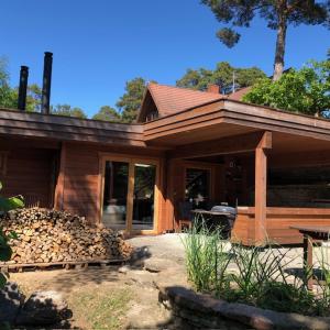 ein Haus mit einem Stapel Feuerholz davor in der Unterkunft Natura Sauna in Laulasmaa