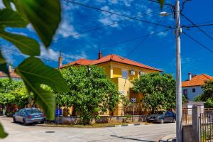 une maison jaune avec des voitures garées devant elle dans l'établissement Nikola apartments free parking BBQ, à Zadar