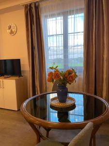 una mesa de cristal con un jarrón de flores. en Casa Diana, en Mihai Viteazu