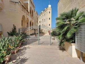 a gate with a palm tree next to a building at East Breeze Penthouse in Mġarr