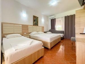 a hotel room with two beds and a chair at Apartments Rudaj in Ulcinj