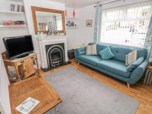 a living room with a blue couch and a tv at 3 Aelybryn in Llanelli