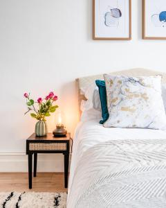 Un dormitorio con una cama con una mesa con un jarrón de flores en Charming 1 Bed Apt in Kensington - Free London Tour Included By City Apartments UK Short Lets Serviced Accommodation, en Londres