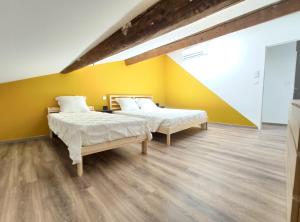 Duas camas num quarto com paredes amarelas e pisos em madeira em ColorChic 3 étoiles - 120m2 Plein centre - Parking Privé Terrasse Clim em Mèze