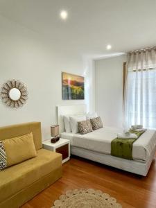 a white bedroom with a bed and a couch at CarreraHouses Canela in Vigo