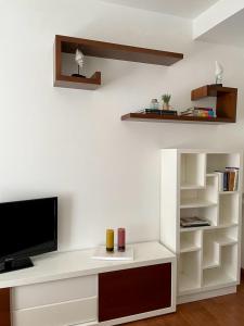 a white living room with a tv and shelves at CarreraHouses Canela in Vigo