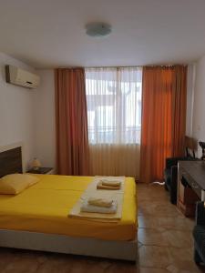 Un dormitorio con una cama amarilla y una ventana en Апартаменти до плажа на Аурелия - между Несебър и Равда, en Nesebar