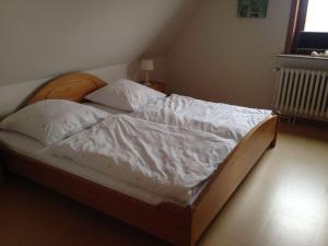 Wohnung-Felsenauster-im-Haus-Muschelgarten في Alkersum: غرفة نوم بسرير ذو شراشف ووسائد بيضاء