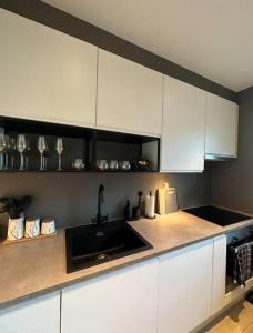 uma cozinha com armários brancos e um lavatório preto em Nytt og flott hus i Haugesund 