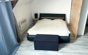 a bedroom with a bed and a ottoman in it at Maisons de vacances 3 lits in Varzy