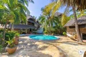 a swimming pool in front of a house with palm trees at Suite Two Rooms - Watamu in Watamu