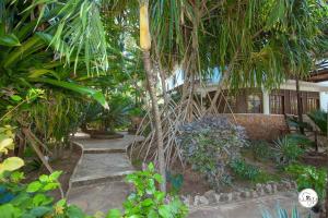 a garden with a palm tree in front of a house at Suite Two Rooms - Watamu in Watamu