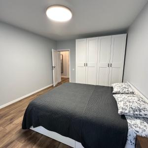 a bedroom with a black bed and white cabinets at Cozy Apartment Kazlų Rūda in Kazlų Rūda