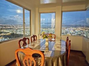 comedor con mesa y algunas ventanas en Espectacular Casa Vacacional !Sorprendente vista!, en Ambato