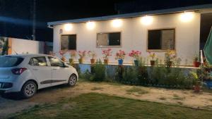 une petite voiture garée devant une maison fleurie dans l'établissement Rangili Baag, à Varanasi