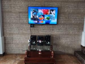 TV de pantalla plana colgada en una pared con altavoces en Espectacular Casa Vacacional !Sorprendente vista!, en Ambato