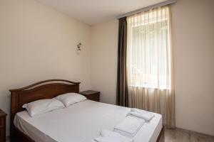 a bedroom with a bed with white sheets and a window at Filaret studios with free parking in Varna City
