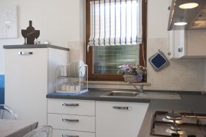 a kitchen with white cabinets and a sink and a window at Casavacanze Azzurro Mare in Porto SantʼElpidio